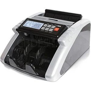 Mesin penghitung uang merek Tissor berwarna perak dan hitam. Alat ini memiliki panel kontrol digital di bagian depan dengan layar LCD yang menampilkan berbagai indikator penghitungan, serta tombol navigasi berwarna hitam dan merah.
